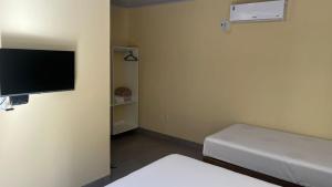 a room with two beds and a flat screen tv at Hotel Rocha in Novo Acordo