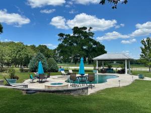 a patio with chairs and umbrellas next to a pool at Deluxe Farm Studio Apt with Pool View in Alachua