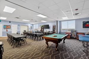 a pool table in a room with tables and chairs at Ocean East Resort Club in Ormond Beach