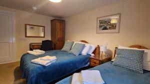 a bedroom with two beds with blue sheets at The Ship Inn Looe in Looe