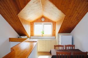 a kitchen with wooden ceilings and a table and chairs at Penzión U Tonky in Tomek