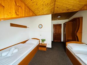 two beds in a room with wooden ceilings at Penzión U Tonky in Tomek