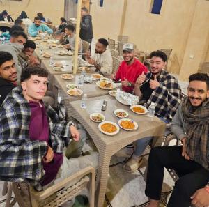 a group of men sitting at a table eating food at King Siwa in Siwa