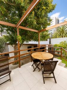 a wooden table and chairs on a patio with a table at 12 On Braemar Guesthouse in Cape Town