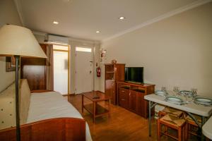a bedroom with a bed and a table and a television at FLH Monte Gordo Balcony Flat in Monte Gordo