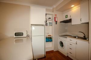 a white kitchen with a refrigerator and a microwave at FLH Monte Gordo Balcony Flat in Monte Gordo