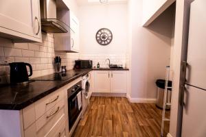 a kitchen with white appliances and a clock on the wall at Chapel Retreat | King Bed | Central Swansea in Swansea