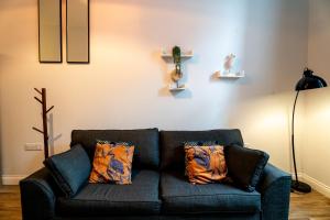 a living room with a blue couch with pillows at Chapel Retreat | King Bed | Central Swansea in Swansea