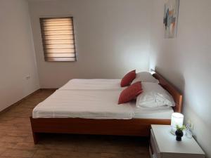 a bedroom with a bed with white sheets and red pillows at Apartment Near Zadar Airport & City in Crno