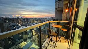 a balcony with two stools and a view of a city at LK Funcionários 6 in Belo Horizonte