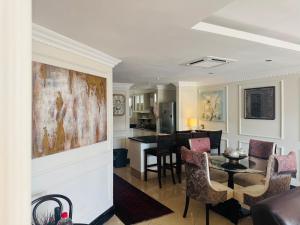 a living room with a table and chairs and a kitchen at The Sails-Luxe Penthouse By Ezey Tours in Durban
