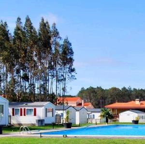a swimming pool in front of houses and trees at Casa da Agueira AC1 in Pataias