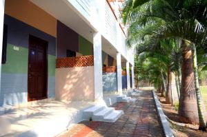 a building with palm trees next to a sidewalk at Megha Resort , Hampi in Hampi