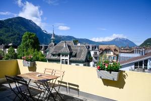a table and chairs on a balcony with mountains at Cozy Swiss Apartment - City & Mountain view in Interlaken