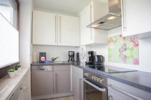 a kitchen with white cabinets and a sink at Welcome in - Ferienwohnung 59-W in Winterberg mit Balkon und Schwimmbad in Winterberg +43 photos