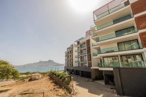 an apartment building with a view of the beach at Sharksproperties Luxury 3BR Ocean View Apartment with Rooftop Pool 6 Guests in Mindelo