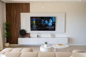 a living room with a tv on a white wall at Sharksproperties Luxury 3BR Ocean View Apartment with Rooftop Pool 6 Guests in Mindelo