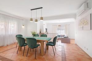 a dining room with a table and green chairs at Modern Villa In Olhao in Quelfes