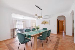 a dining room with a table and green chairs at Modern Villa In Olhao in Quelfes