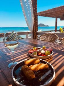 a table with a plate of food and a glass of wine at Porto Koukla Beach in Lithakia