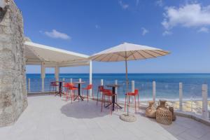a patio with tables and chairs and an umbrella on the beach at Aldiana Club Rocca Nettuno Calabria in Tropea