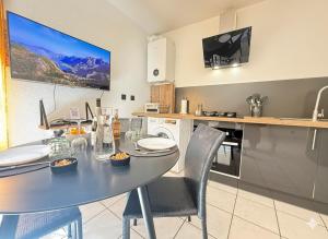 a kitchen with a table and chairs and a tv at Le Domi Hyper Centre Proche Cols Stations in Saint-Jean-de-Maurienne