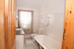 a bathroom with a tub and a toilet and a sink at Hobbit Boutique Hotel in Bloemfontein +52 photos