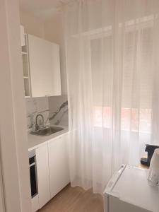 a white kitchen with a sink and a window at Novelli Homes in Formigine
