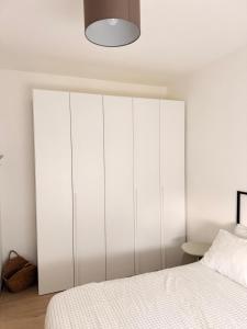 a white bedroom with a bed and a white cabinet at Novelli Homes in Formigine