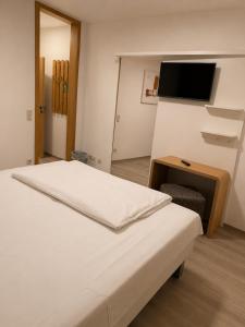 a bedroom with a bed and a table and a tv at Hotel Eurocity in Bruchköbel