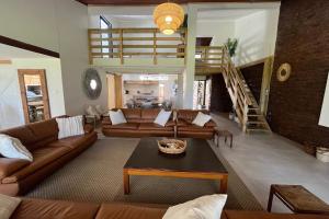 a living room with leather couches and a staircase at SeaWaves Beach House, Shelly Beach in Shelly Beach