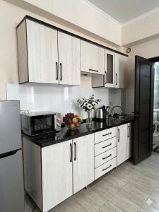 a kitchen with white cabinets and a black refrigerator at Гостевой дом Кымбат in Chok-Tal