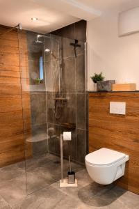 a bathroom with a toilet and a glass shower at EulenNest - Ferienhaus in Seeboden am Millstätter See mit Bergblick & Sauna in Seeboden