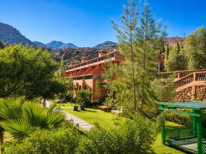 a building with a garden with trees and mountains at Aurocher Marrakech Ourika Oukaimeden in Oukaïmeden