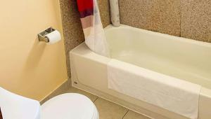 a bathroom with a toilet and a tub and a toilet paper roll at Relax Inn Bloomsburg in Bloomsburg