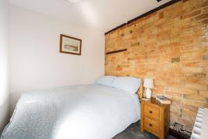 a bed in a bedroom with a brick wall at 2 Bed in Thurleigh oc-o42689 in Thurleigh