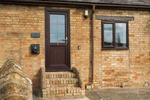 a brick building with a brown door and two windows at 2 Bed in Thurleigh oc-o42689 in Thurleigh