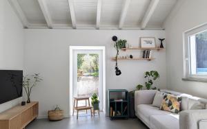 a living room with a couch and a tv at OKTO Beach House in Praia do Almoxarife