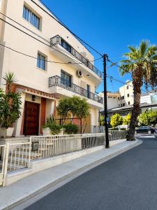 a building with a fence and palm trees on a street at Smart Deluxe Studio N9 private Kitchenette Balcony Beach 250m Marina Port 900m in Limassol