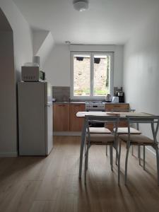 a kitchen with a table with chairs and a refrigerator at le chardonneret in Commer