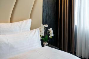 a bed with white pillows and a vase with flowers at PLAZA Residence Mannheim in Mannheim