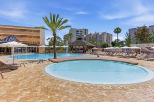a large swimming pool with chairs and umbrellas at Aquasol Aparthotel in Palmanova