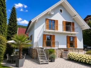 a white house with a palm tree in front of it at EulenNest - Ferienhaus in Seeboden am Millstätter See mit Bergblick & Sauna in Seeboden