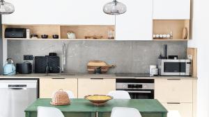 a kitchen with a green table and white cabinets at OKTO Beach House in Praia do Almoxarife