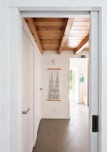 a hallway with white walls and a wooden ceiling at OKTO Beach House in Praia do Almoxarife