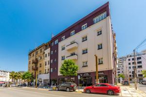 a red car parked in front of a building at Hotel Aquila D in Durrës