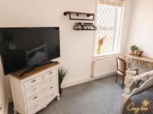 a living room with a flat screen tv on a dresser at Cosy Bee in Bournemouth
