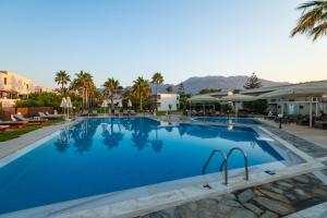 a pool at a resort with mountains in the background at Happy Days Beach Hotel in Georgioupolis +18 photos