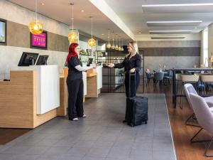 two women shaking hands in a restaurant with luggage at ibis Karlsruhe Hauptbahnhof in Karlsruhe