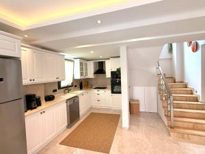 a kitchen with white cabinets and a staircase at As Villas Villa Asil in Fethiye